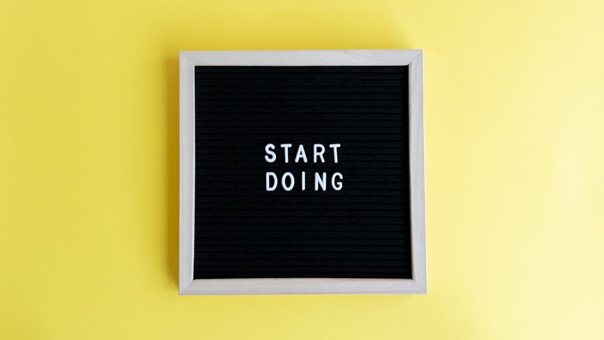Black message board with 'Start Doing' on a bright yellow background for inspiration.